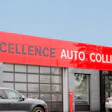 Red and gray Excellence Auto Collision repair shop exterior with parked vehicles