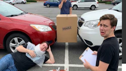 Comedic scene of two people with a fragile box and spilled ketchup in parking lot