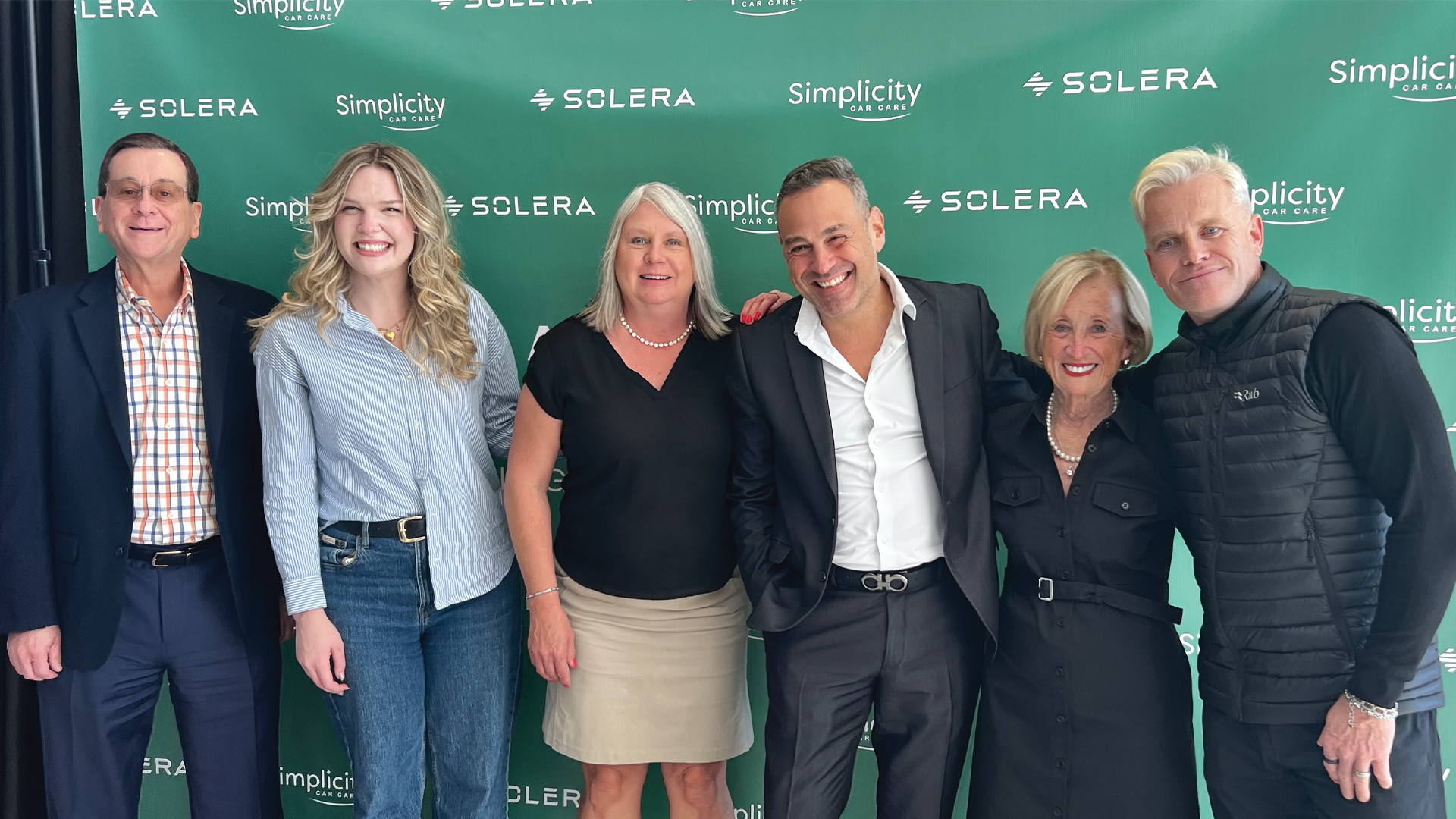 Six professionals posing in front of Solera and Simplicity corporate backdrop