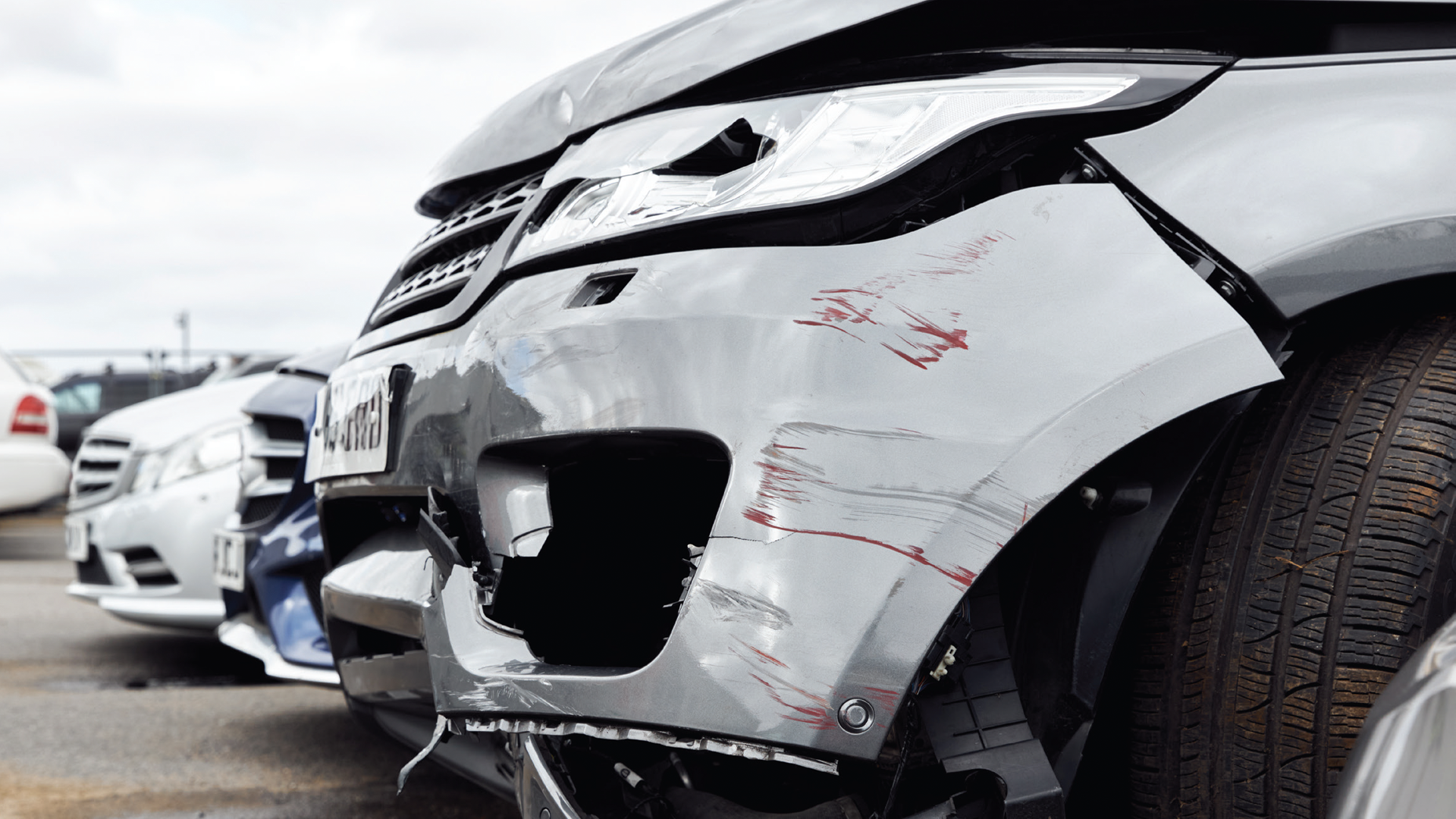 White SUV with front bumper damage and red scratch marks in parking lot