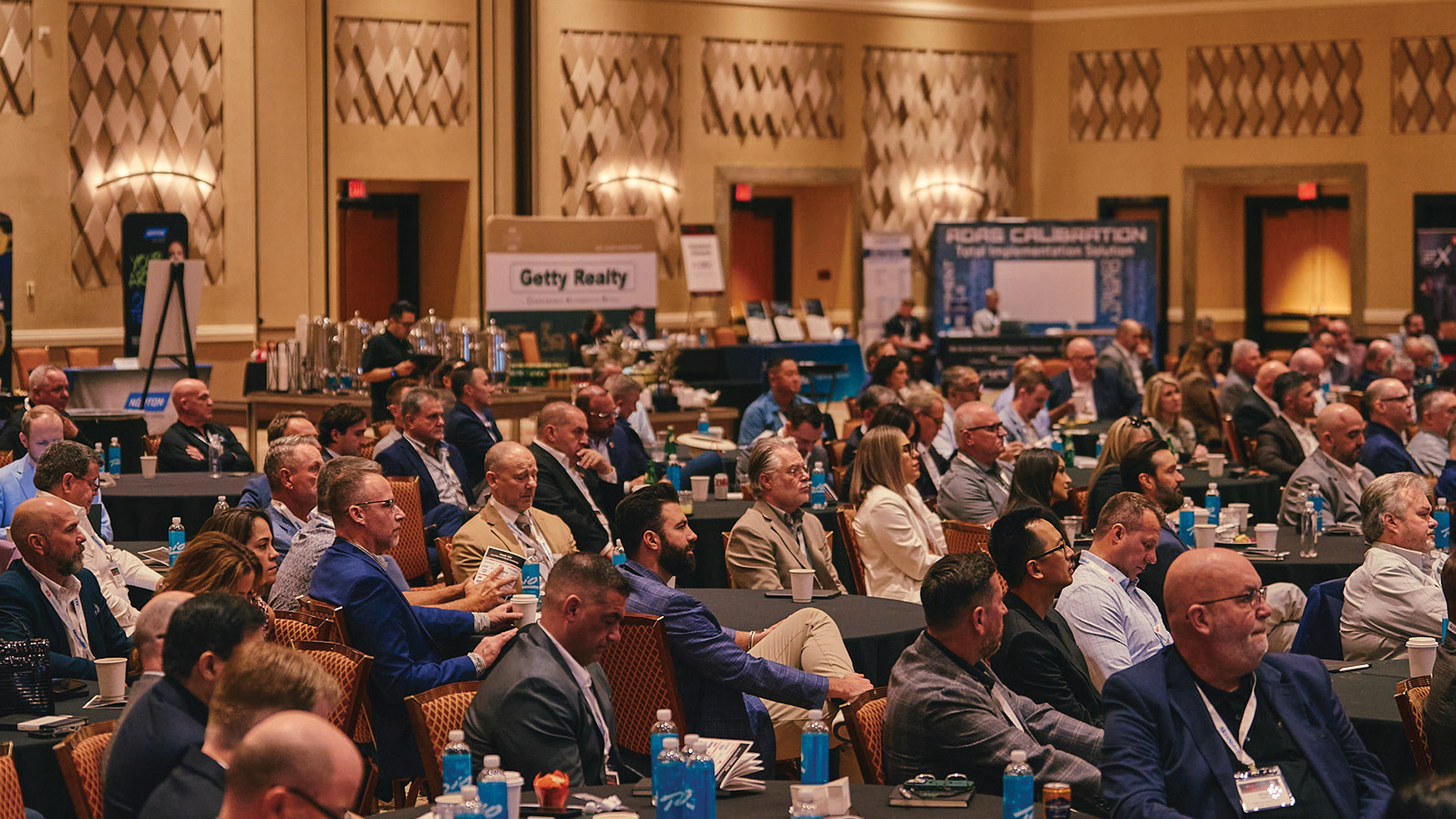 Large conference room filled with business professionals at seated event