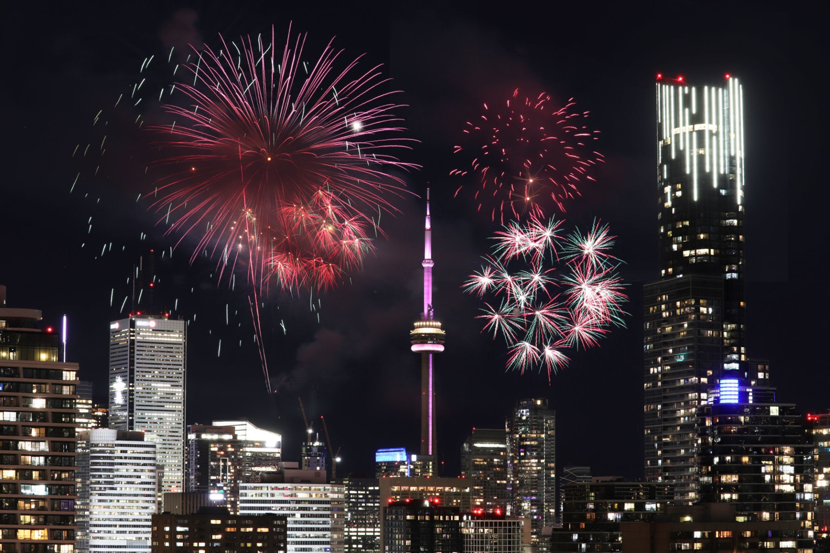 Toronto skyline at night with vibrant red and pink fireworks