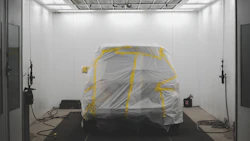 Vehicle draped in white protective sheet with yellow tape in sterile white room