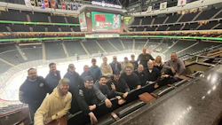 Group of people seated together at hockey arena with empty stands