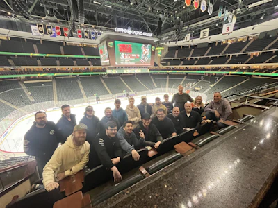 Group of people seated together at hockey arena with empty stands