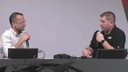 Two professionals speaking with microphones at a conference table