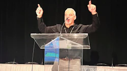 Speaker gesturing passionately at a transparent podium during presentation
