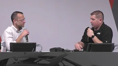 Two professionals speaking with microphones at a conference table