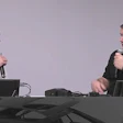 Two professionals speaking with microphones at a conference table