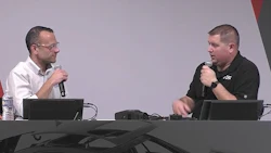 Two professionals speaking with microphones at a conference table