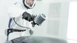 Auto painter in protective gear using spray gun on vehicle surface