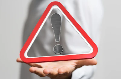 Red warning triangle with exclamation point hovering above an open hand