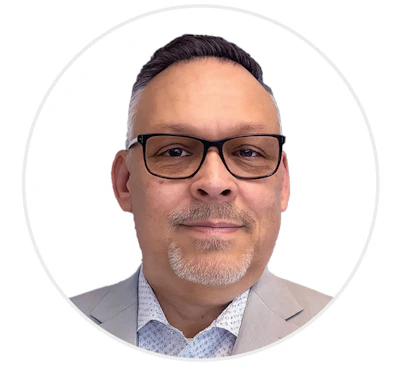 Professional headshot of a man in glasses and light gray blazer