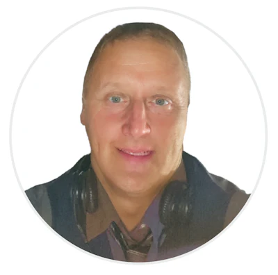 Professional headshot of smiling man in dark vest with headphones