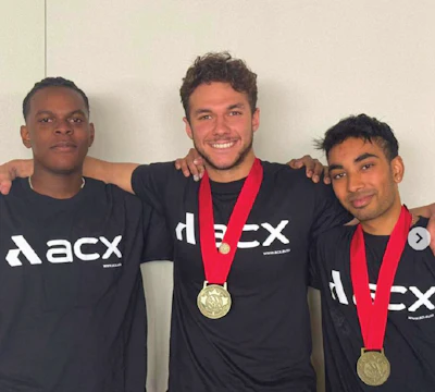 Three ACX team members wearing black shirts, displaying gold medals
