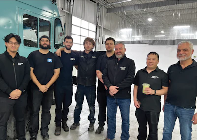 Team of eight workers in black uniforms standing together in industrial warehouse