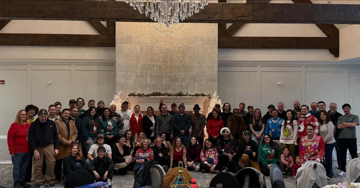 Large group of people in festive holiday sweaters gathered for team photo