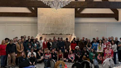Large group of people in festive holiday sweaters gathered for team photo