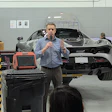 Person speaking with microphone in automotive workshop near high-end sports car