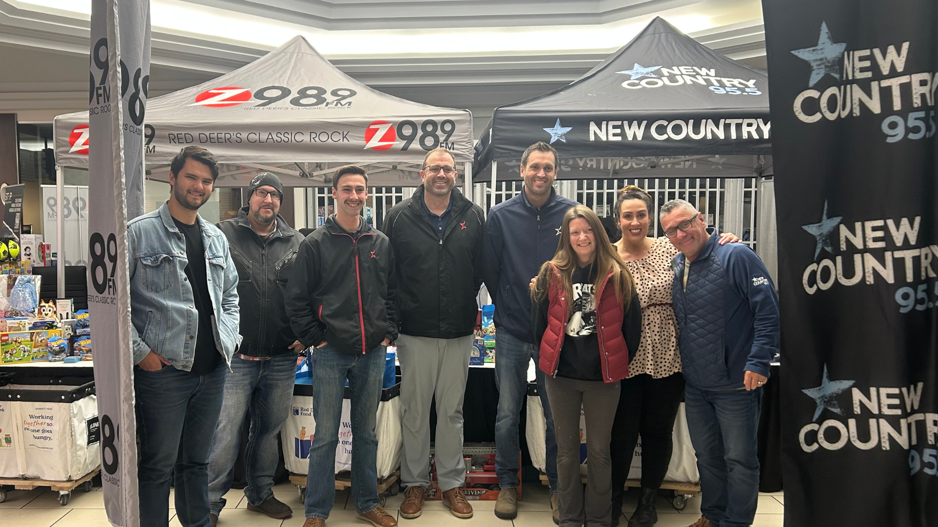 Radio station team posing at promotional event with branded tents
