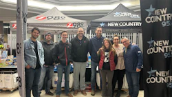 Radio station team posing at promotional event with branded tents