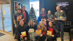 Group of people holding board games in front of Christmas tree