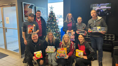 Group of people holding board games in front of Christmas tree