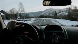 Driving on a snow-covered mountain road with winter landscape and hills in background
