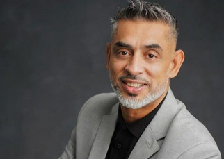 Professional portrait of a smiling middle-aged man in gray blazer