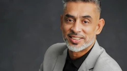 Professional portrait of a smiling middle-aged man in gray blazer