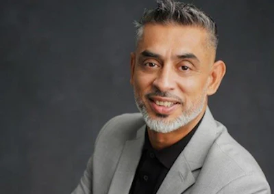 Professional portrait of a smiling middle-aged man in gray blazer