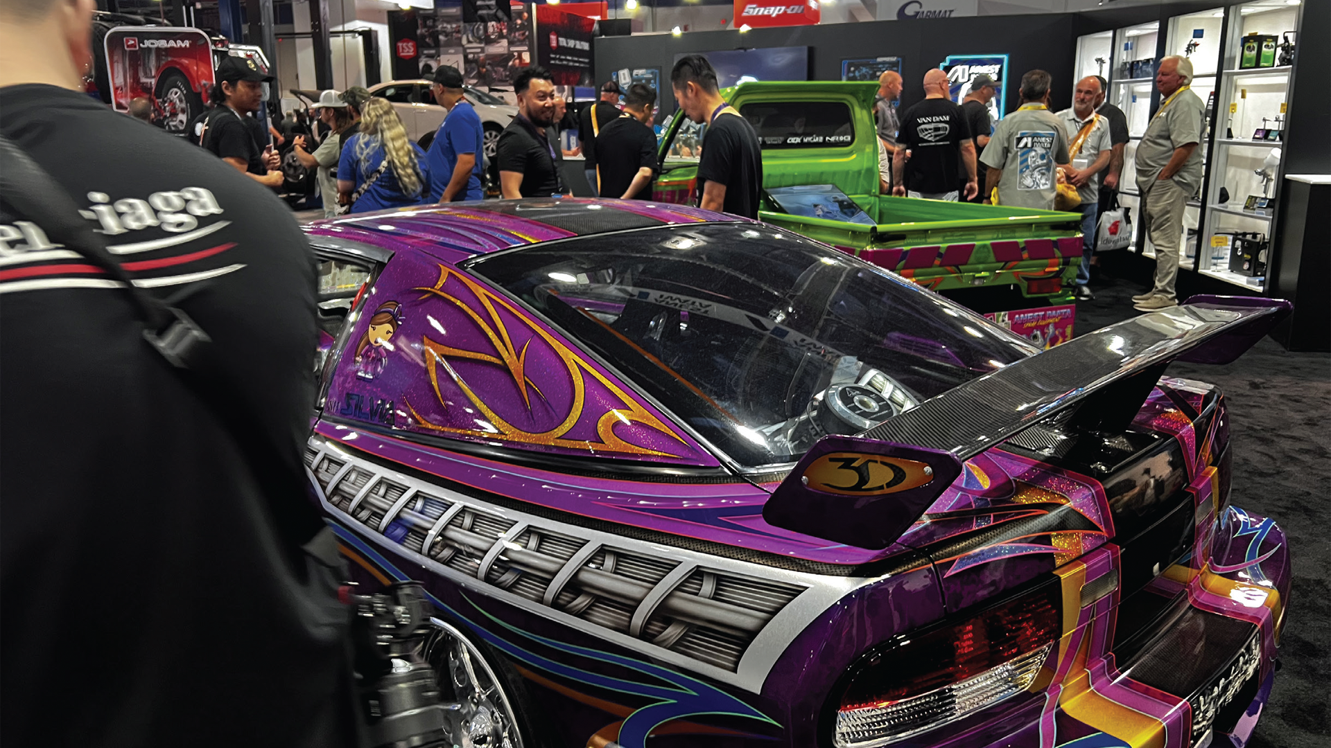 Custom purple racing car with intricate pinstripe design at automotive trade show
