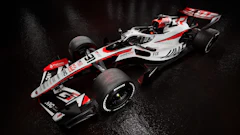 Haas Formula 1 racing car with white, red, and black livery on wet surface