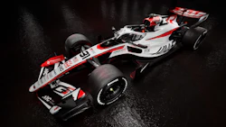 Haas Formula 1 racing car with white, red, and black livery on wet surface