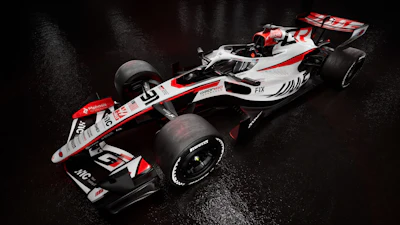 Haas Formula 1 racing car with white, red, and black livery on wet surface
