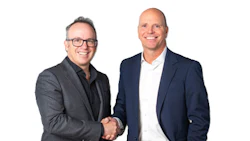 Two businessmen in professional attire shaking hands and smiling
