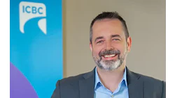 Smiling professional in gray suit with ICBC logo backdrop