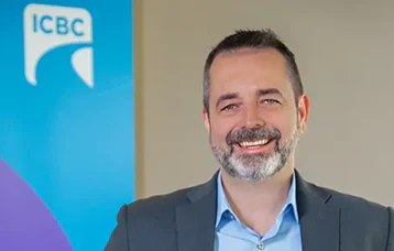 Smiling professional in gray suit with ICBC logo backdrop