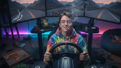 Person in colorful jacket driving simulator with mountain road backdrop