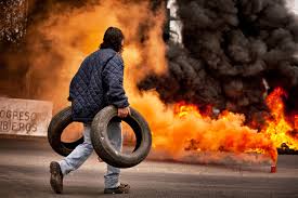 Protester with tire near burning flames during street demonstration