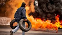 Protester with tire near burning flames during street demonstration