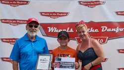 Three people posing at Wheels on the Danforth automotive event with branded backdrop