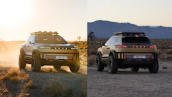 Two futuristic electric SUVs on dusty terrain with mountain backdrop at sunset