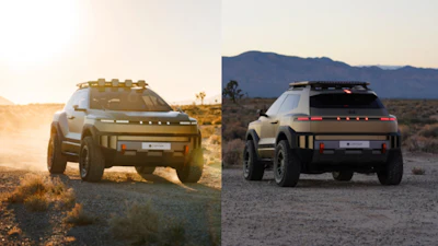 Two futuristic electric SUVs on dusty terrain with mountain backdrop at sunset