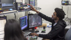 Technical professional adjusting equipment in electronics laboratory workspace