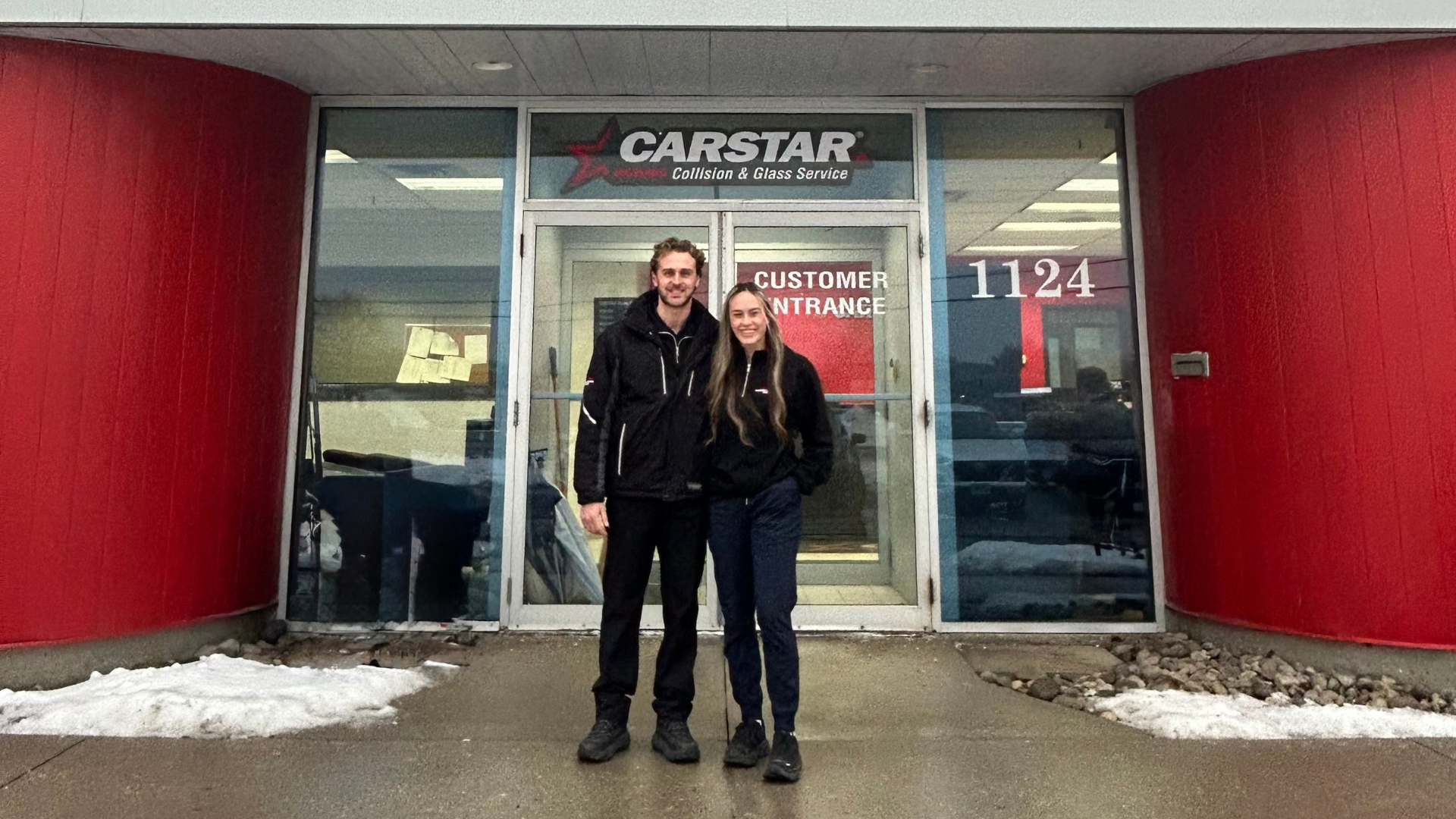 CARSTAR auto collision repair shop entrance with two people standing outside