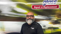 Bald professional with gray beard wearing Novus glass repair uniform