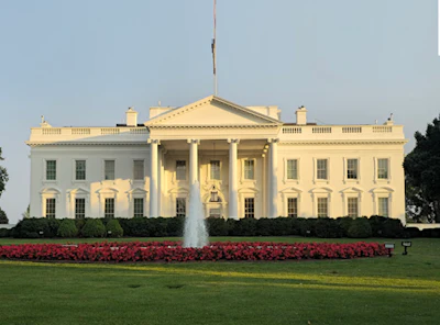White House with red flower garden and fountain on sunny day