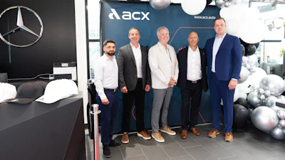 Five businessmen posing at Mercedes-Benz dealership with ACX event backdrop
