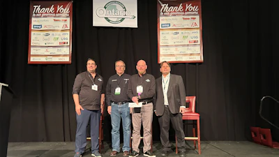 Four professionals on stage at Ontario conference with sponsor recognition boards